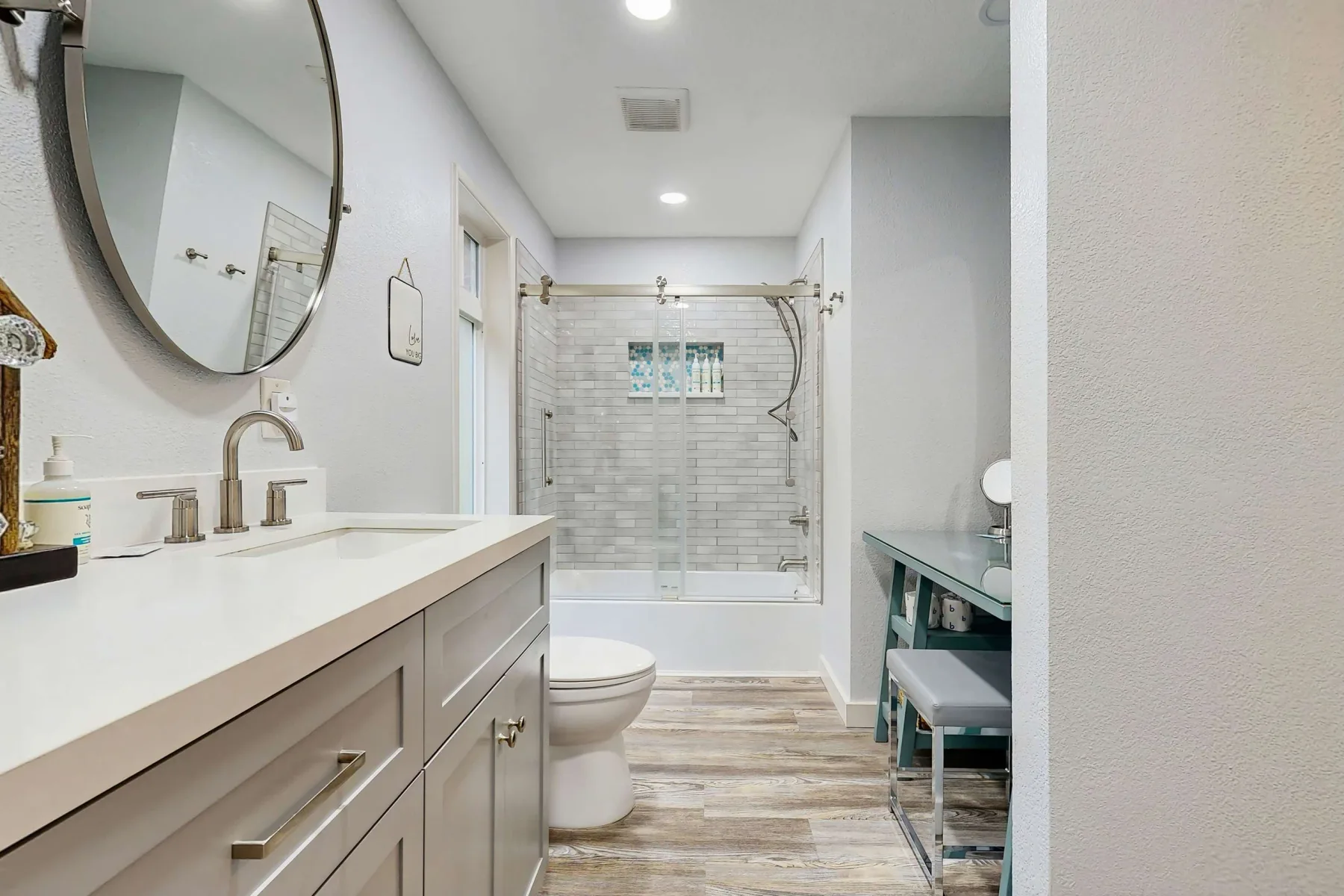Un baño luminoso con un tocador largo y una ducha con mampara de vidrio.
