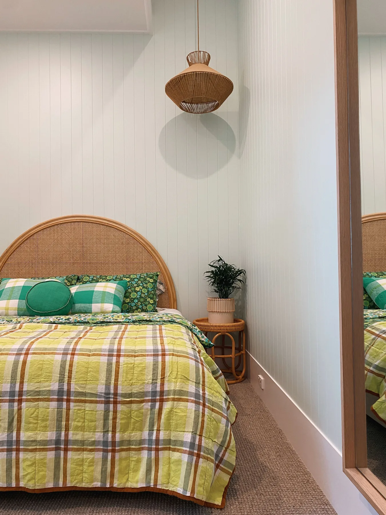 Un dormitorio con una cama cubierta con una colcha de cuadros verdes y amarillos.