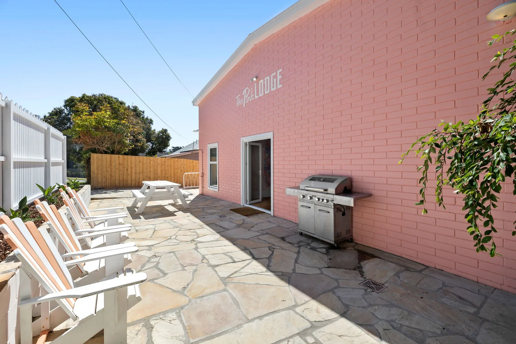 Un patio al aire libre con asientos y una parrilla junto a un edificio rosa.