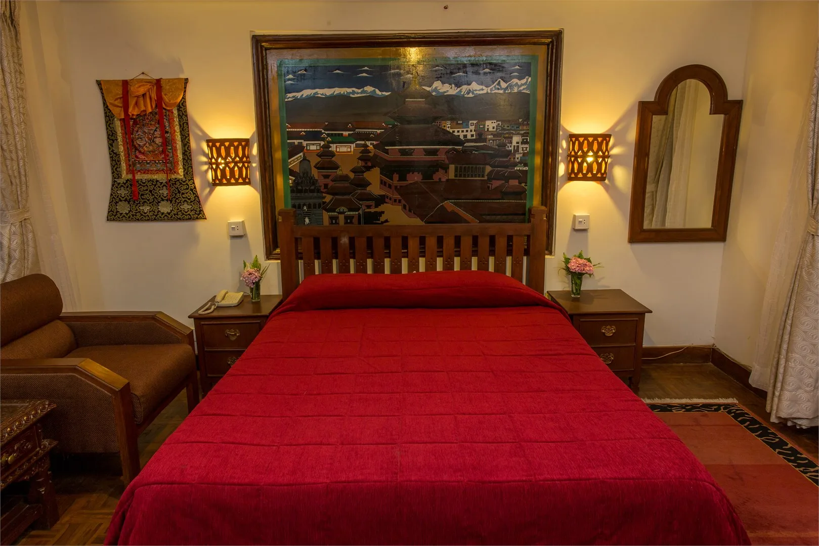 Espacio representativo del hotel: Un dormitorio con una cama roja, mesitas de noche y un paisaje enmarcado.