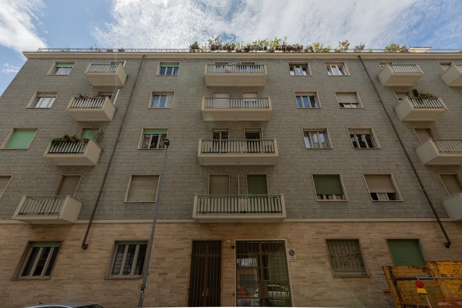Shared amenity: Apartment building exterior with balconies and windows under a partly cloudy sky.