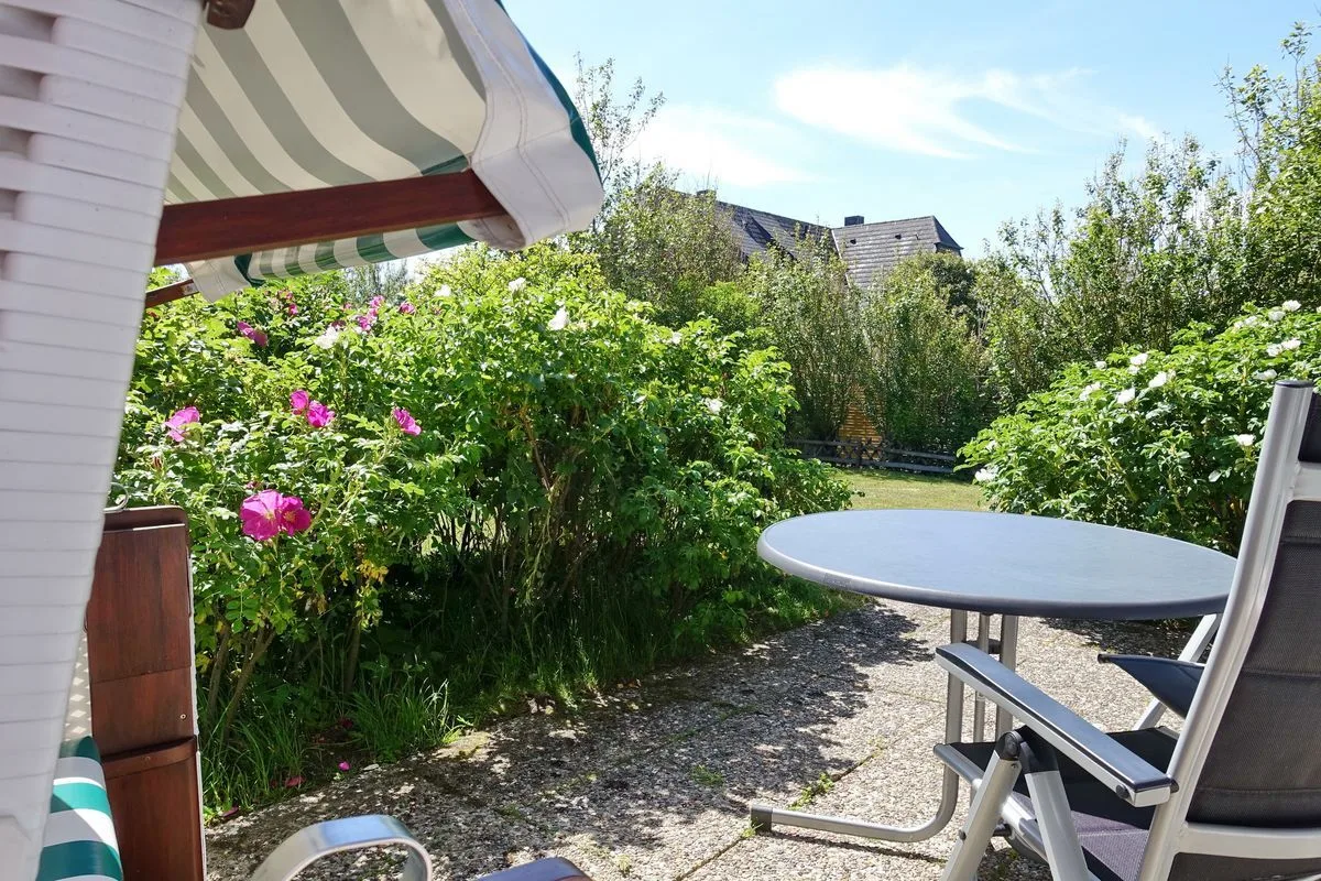 A garden patio with outdoor seating and flowering shrubs.