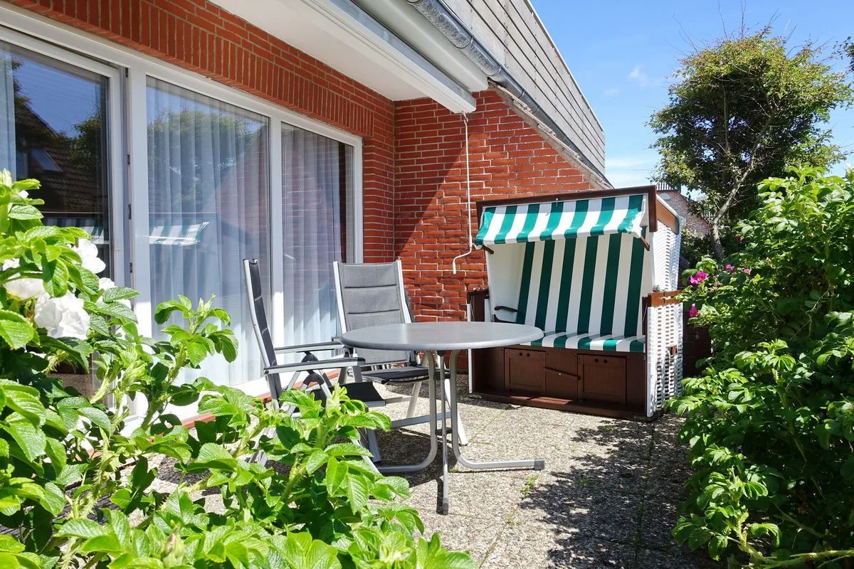 A patio with outdoor seating and a striped beach hut beside a brick house.