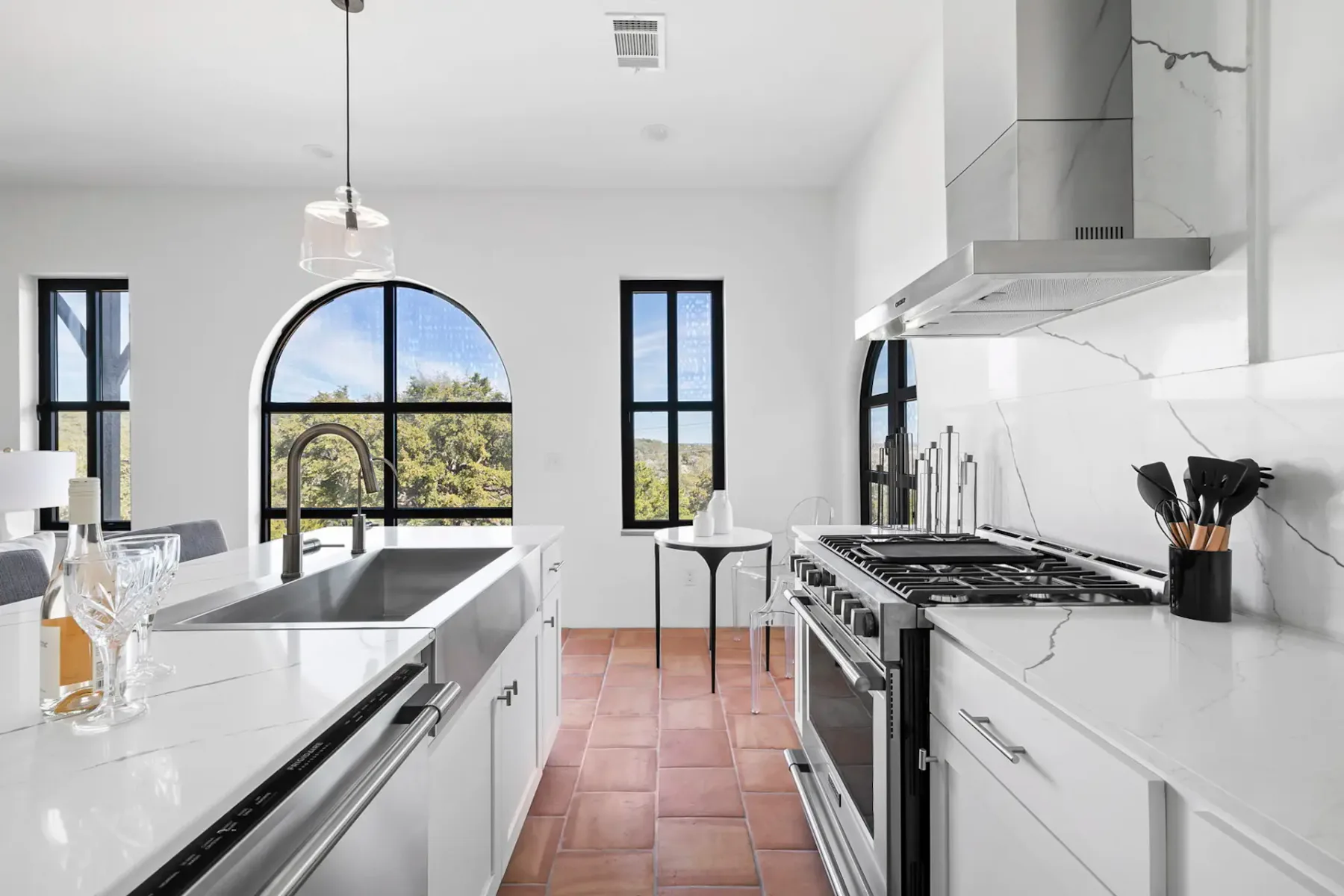 A bright modern kitchen with a large island and arched window.