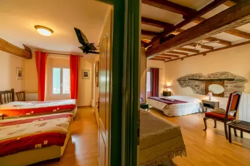 Espacio representativo del hotel: Un dormitorio con dos camas, una ventana y vigas expuestas en el techo.