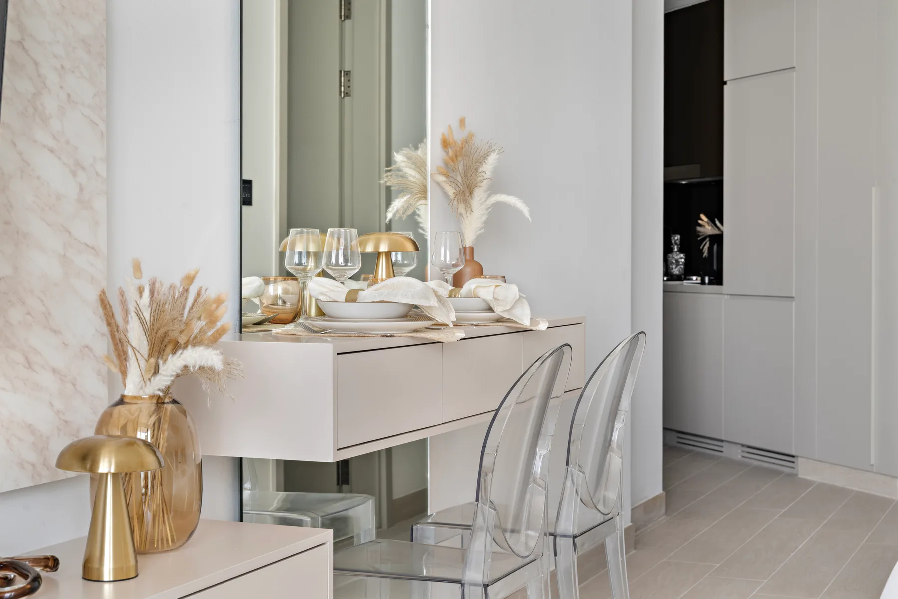 Un comedor luminoso con una mesa, asientos transparentes y flores decorativas.