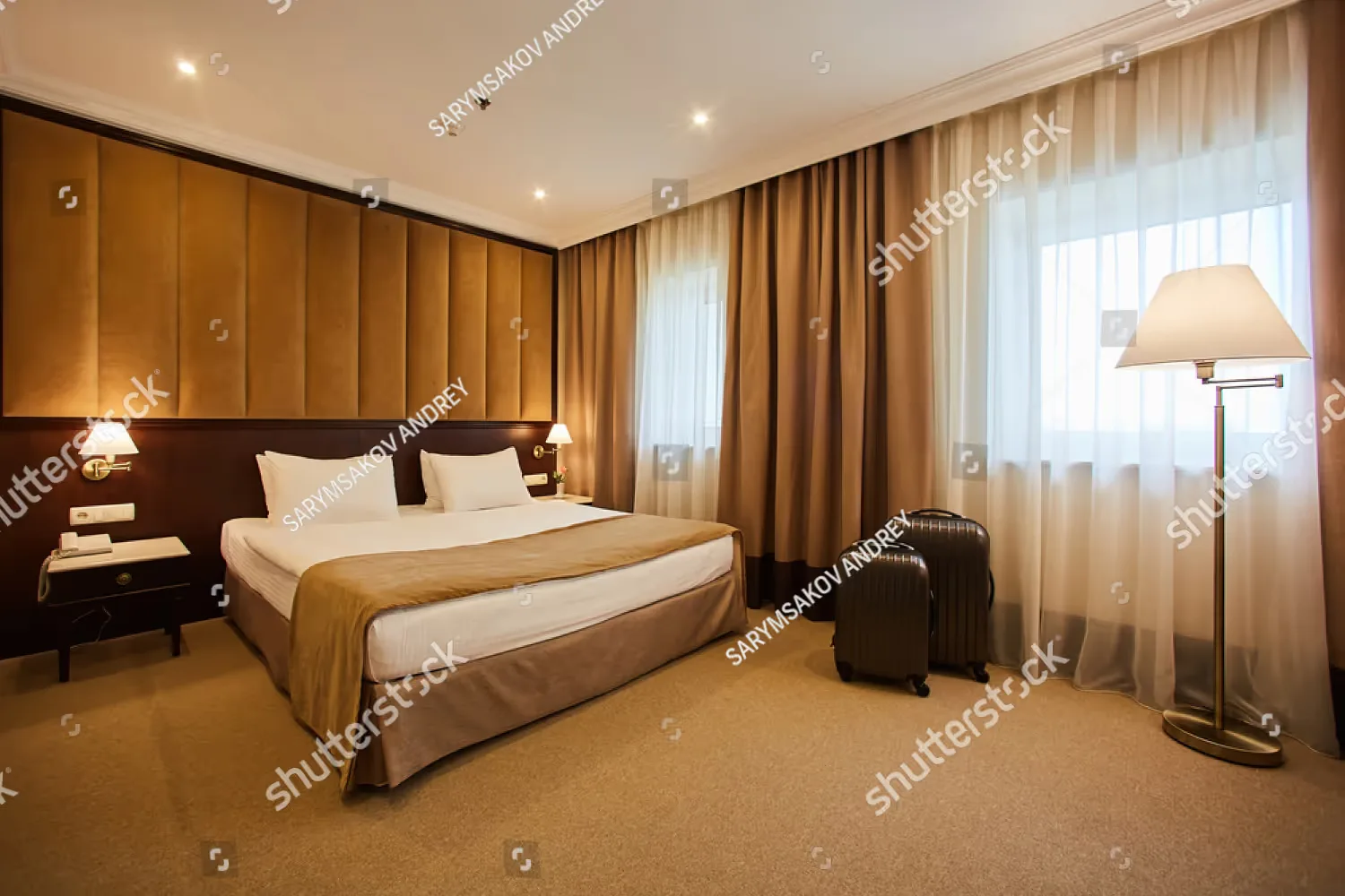 Representative hotel space: A bedroom with a neatly made bed, bedside tables, and curtained windows.