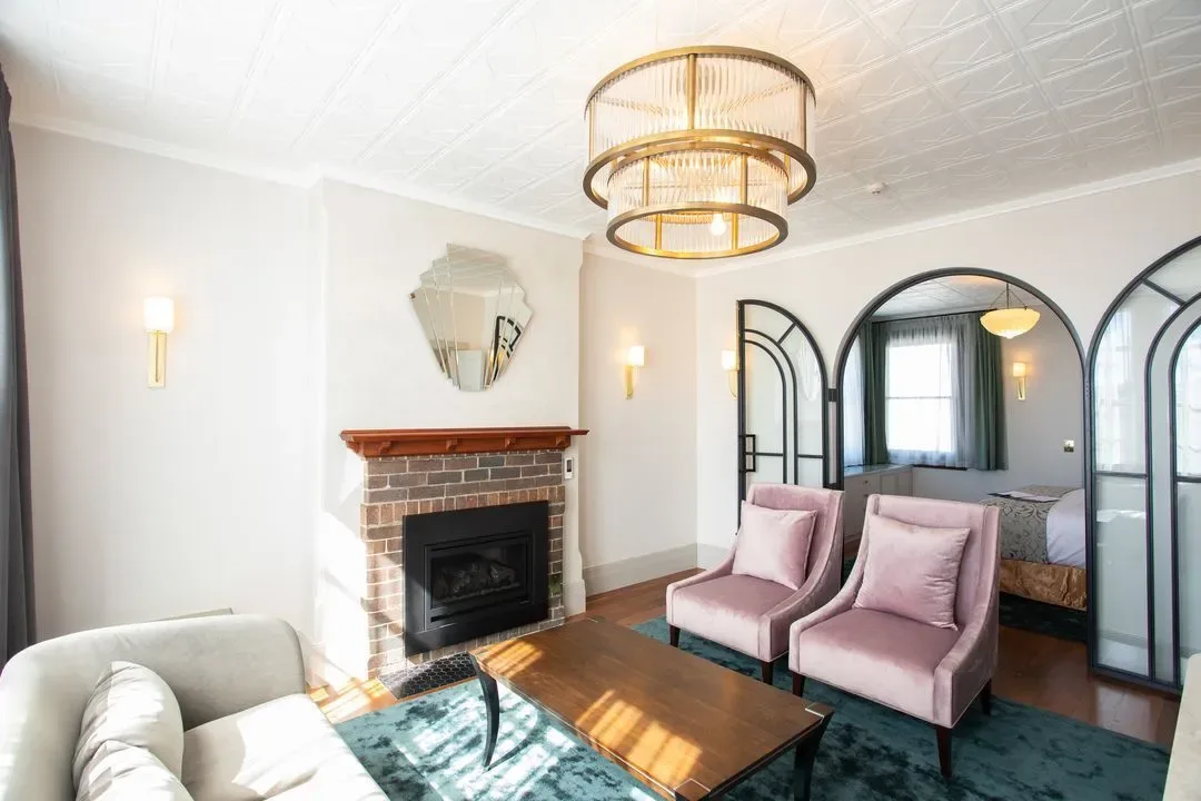 Representative hotel space: A living room with pink seating, a fireplace, and an arched opening.
