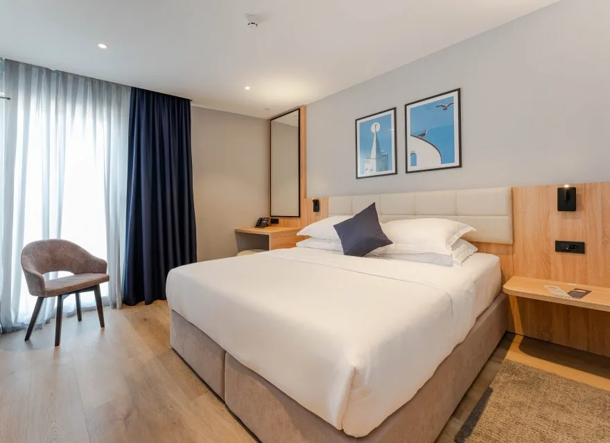 Espacio representativo del hotel: Un dormitorio de hotel luminoso con una cama grande y una silla junto a la ventana.
