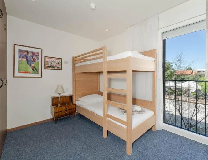 Espacio representativo del hotel: Un dormitorio con una litera de madera junto a una ventana grande.