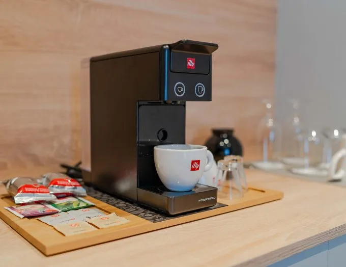 Espacio representativo del hotel: Una cafetera y una taza están sobre una bandeja con sobres en una encimera.