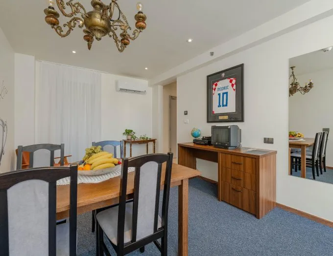 Espacio representativo del hotel: Comedor con una mesa de madera, sillas y un mueble bajo una camiseta deportiva enmarcada.