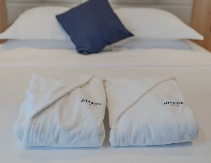 Espacio representativo del hotel: Una cama bien arreglada con toallas blancas dobladas y una almohada oscura.