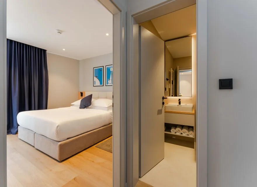 Espacio representativo del hotel: Se ve un dormitorio con la cama hecha junto a una puerta abierta al baño.