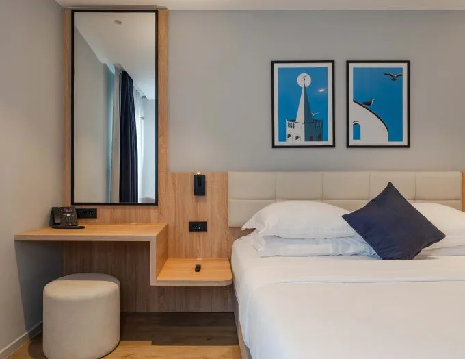 Espacio representativo del hotel: Un dormitorio con una cama tendida y cuadros azules enmarcados sobre el cabecero.