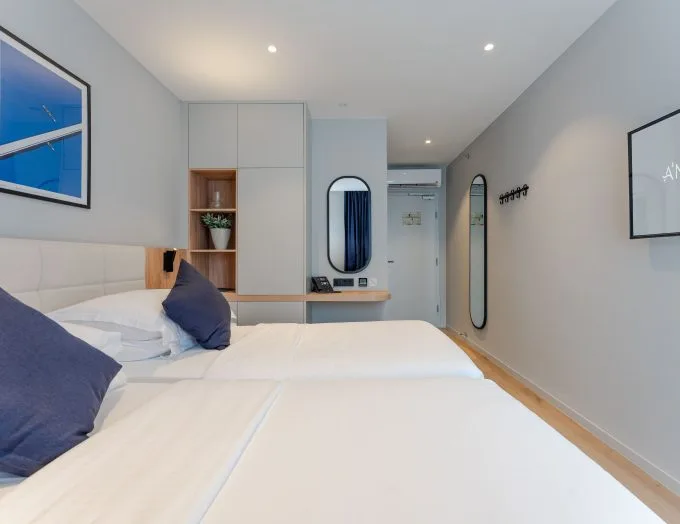 Espacio representativo del hotel: Un dormitorio luminoso de hotel con dos camas y un escritorio integrado.