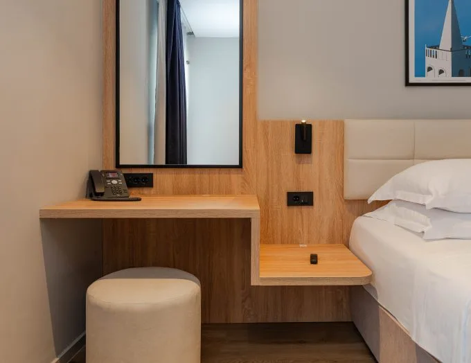 Espacio representativo del hotel: Un dormitorio de hotel con una cama junto a un escritorio de madera y un espejo.