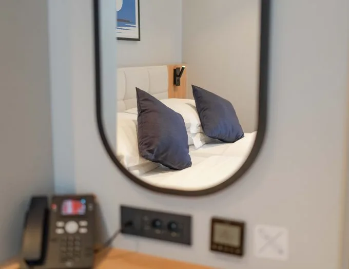 Espacio representativo del hotel: Un dormitorio se refleja en un espejo de pared sobre un escritorio.