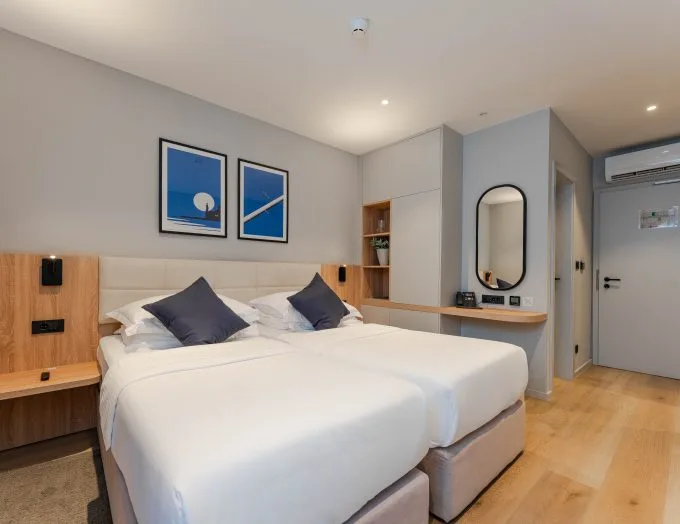 Espacio representativo del hotel: Dormitorio de hotel con dos camas y cuadros enmarcados sobre ellas.