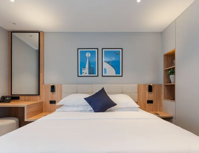 Espacio representativo del hotel: Un dormitorio con la cama tendida y cuadros enmarcados sobre el cabecero.