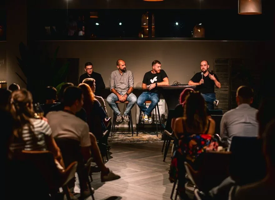 Espacio representativo del hotel: Un público sentado escucha a los ponentes durante un debate en una sala con poca luz.
