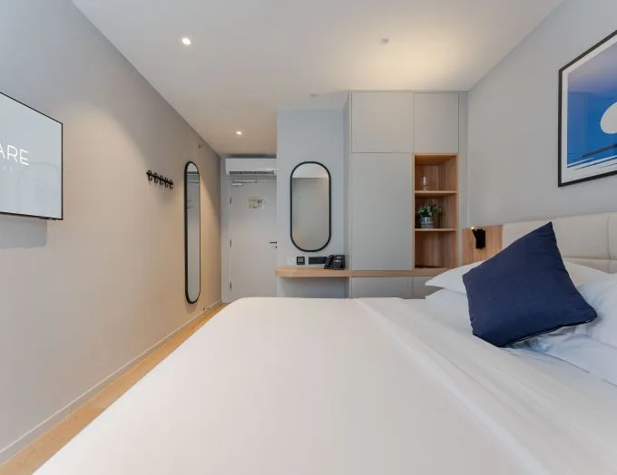 Espacio representativo del hotel: Un dormitorio moderno con una cama bien tendida y almacenamiento integrado.