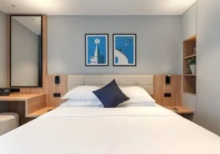Espacio representativo del hotel: Un dormitorio con una cama arreglada y cuadros enmarcados sobre el cabecero.