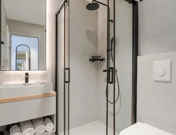 Espacio representativo del hotel: Un baño moderno con una ducha de vidrio y un lavabo.