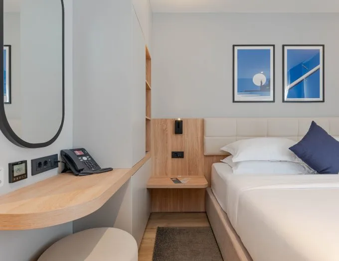 Espacio representativo del hotel: Un dormitorio de hotel con una cama tendida, una mesita de noche y cuadros en la pared.