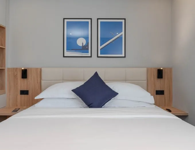 Espacio representativo del hotel: Un dormitorio ordenado con ropa de cama blanca y cuadros enmarcados sobre la cama.