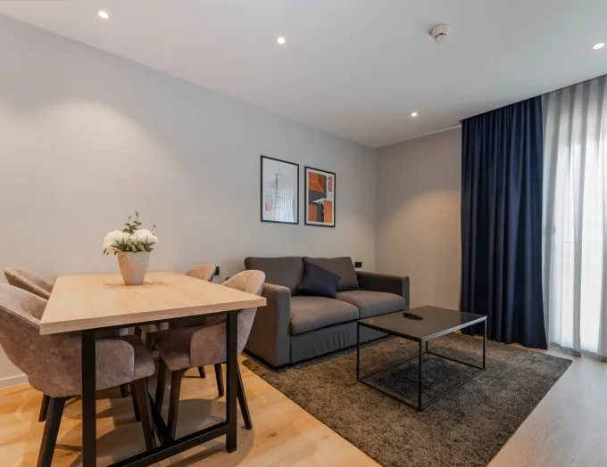 Espacio representativo del hotel: Sala de estar y comedor con asientos, una mesa y cortinas.