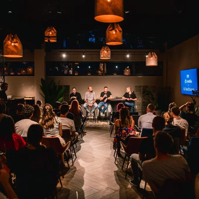 Espacio representativo del hotel: Un público sentado observa un panel de conversación en una sala de eventos con poca luz.