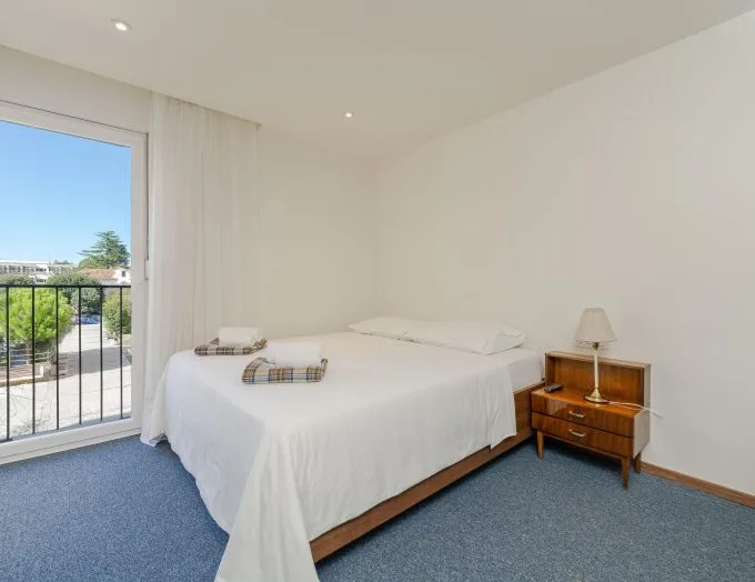 Espacio representativo del hotel: Dormitorio con una cama bien tendida junto a una ventana y una mesita de noche.