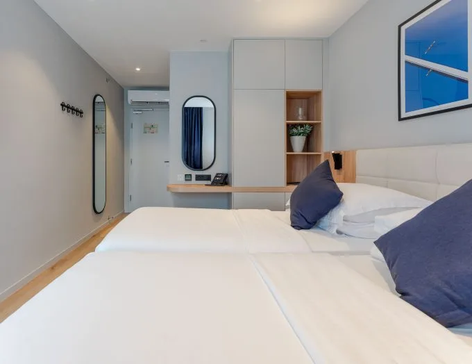 Espacio representativo del hotel: Un dormitorio luminoso con ropa de cama blanca y un escritorio integrado.
