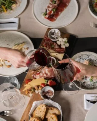 Espacio representativo del hotel: Una mesa de comedor con platos de comida, pan y copas de vino tinto.