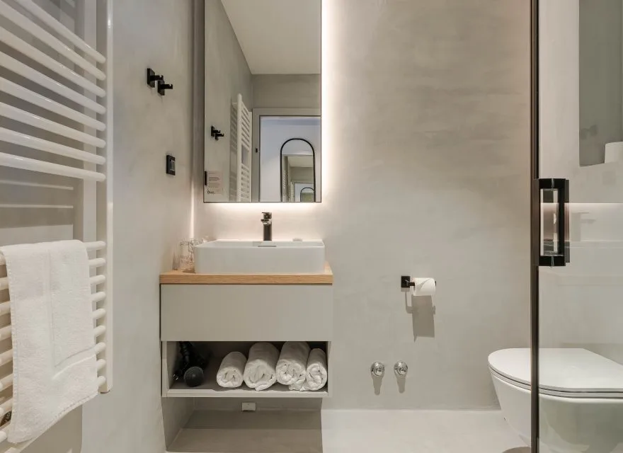 Espacio representativo del hotel: Un baño moderno con lavabo, espejo y panel de ducha de vidrio.