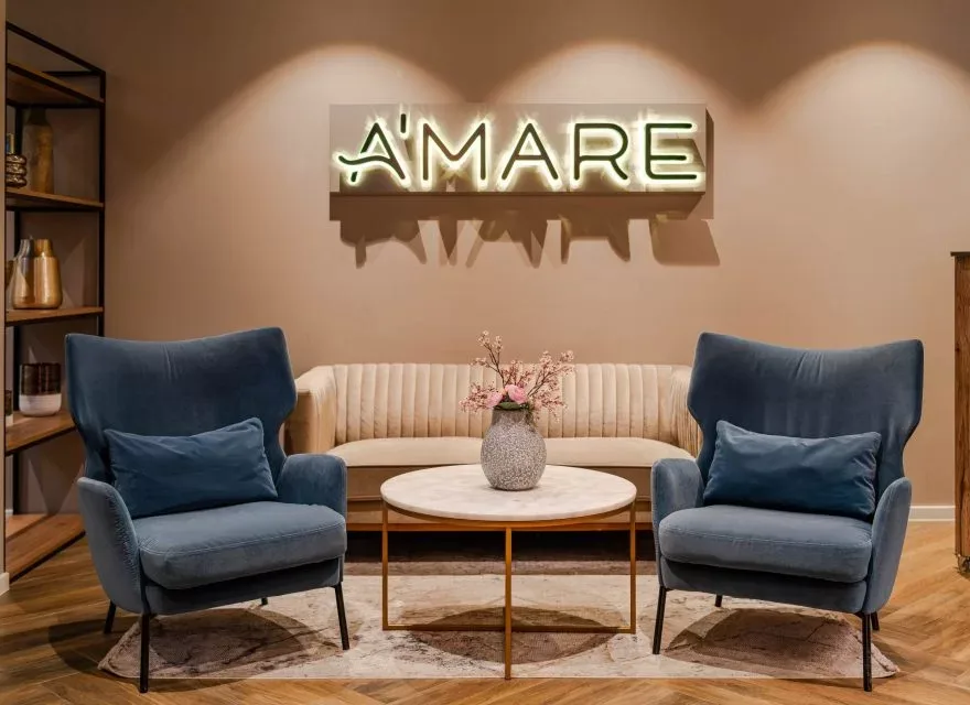 Espacio representativo del hotel: Un salón de hotel con asientos azules y una mesa redonda bajo un letrero iluminado.