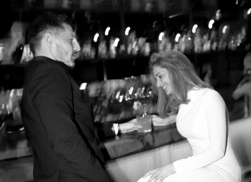 Espacio representativo del hotel: Una pareja comparte una bebida en un bar con botellas.