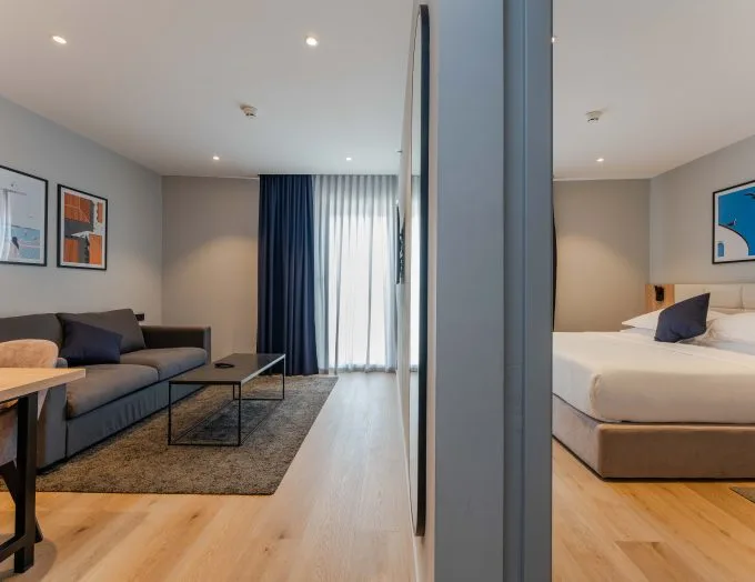 Espacio representativo del hotel: Se ven un dormitorio y una zona de estar a ambos lados de un tabique central.