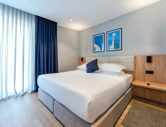 Espacio representativo del hotel: Un dormitorio de hotel con una cama tendida y cortinas azules.