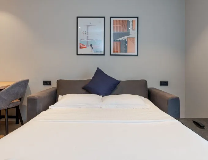 Espacio representativo del hotel: Dormitorio con una cama bien tendida y cuadros enmarcados sobre el cabecero.