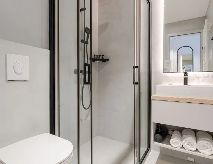 Espacio representativo del hotel: Un baño luminoso con ducha, lavabo y toallas.