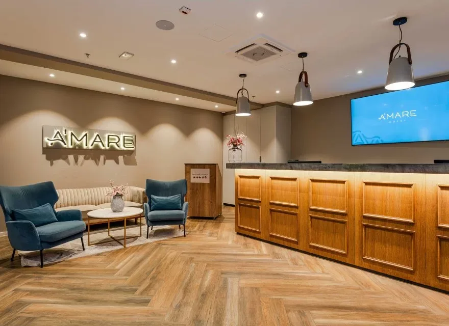 Espacio representativo del hotel: Recepción de hotel con un mostrador de madera y asientos.