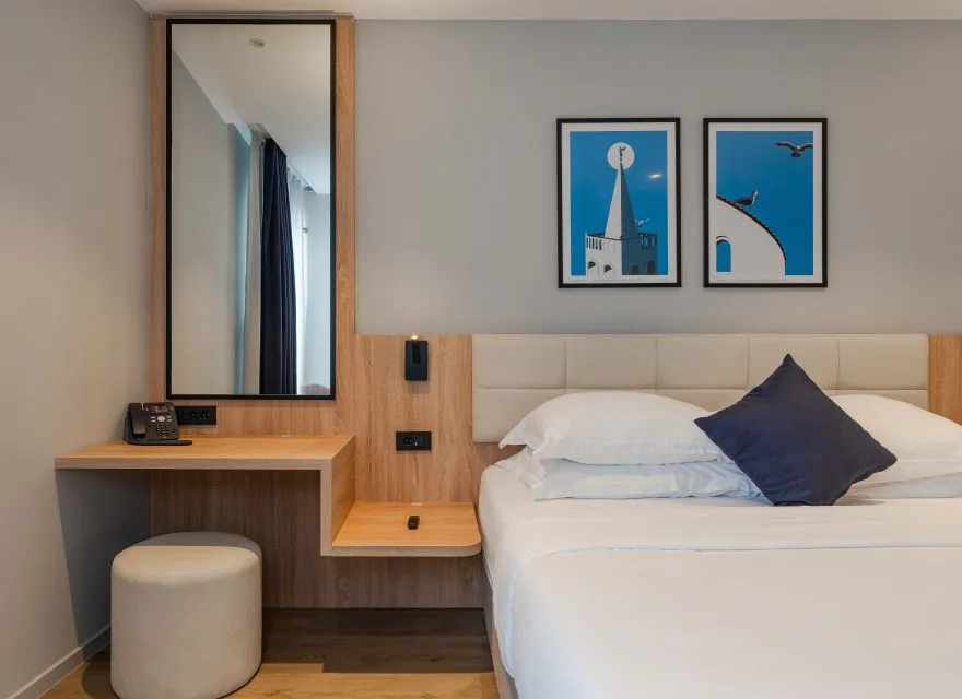 Espacio representativo del hotel: Un dormitorio de hotel con una cama bien tendida y cuadros sobre el cabecero.