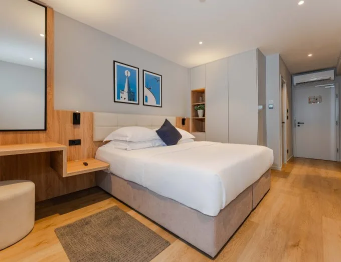 Espacio representativo del hotel: Un dormitorio con una cama bien arreglada y cuadros enmarcados sobre el cabecero.