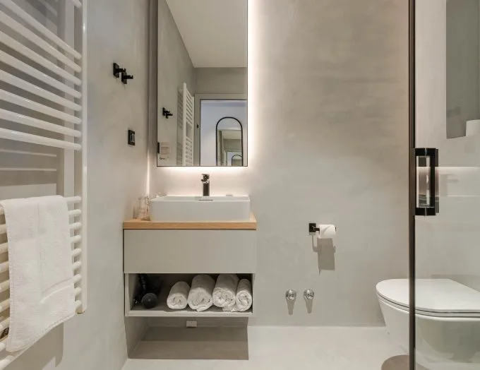 Espacio representativo del hotel: Un baño luminoso con lavabo, espejo e inodoro.