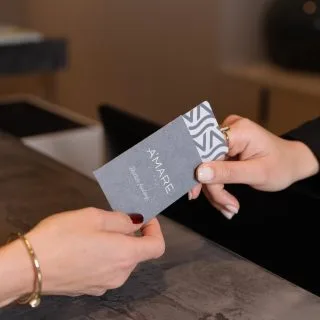 Espacio representativo del hotel: Una mano sostiene una tarjeta gris sobre una encimera.