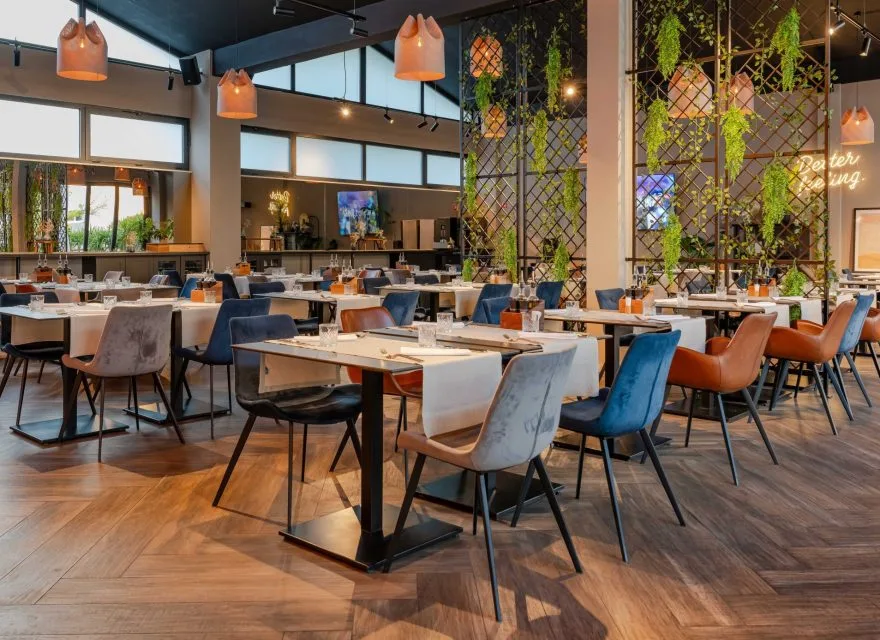 Espacio representativo del hotel: Un comedor de restaurante con mesas, asientos y lámparas colgantes.