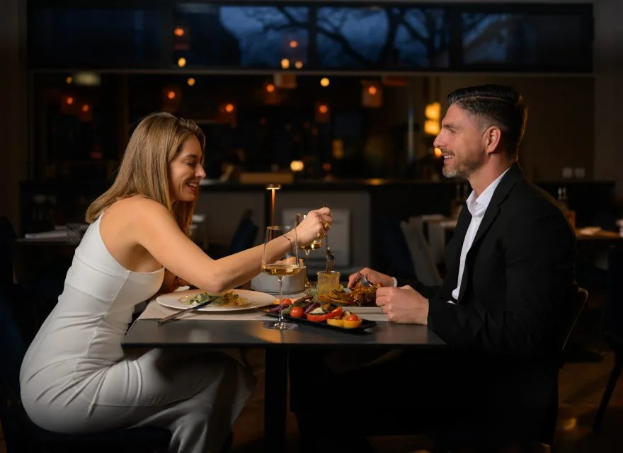 Espacio representativo del hotel: Una pareja comparte la cena en una mesa de restaurante, en un comedor con poca luz.