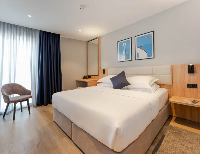 Espacio representativo del hotel: Un dormitorio de hotel con una cama grande, mesas de noche y cuadros enmarcados.